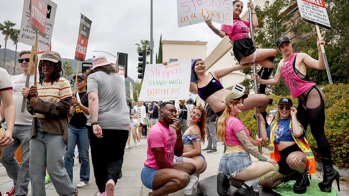 Strippers hold signs and pose on a pole in Hollywood, California