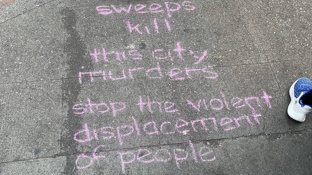 Chalk writing says "sweeps kill, this city murders, stop the violent displacement of people" in Seattle