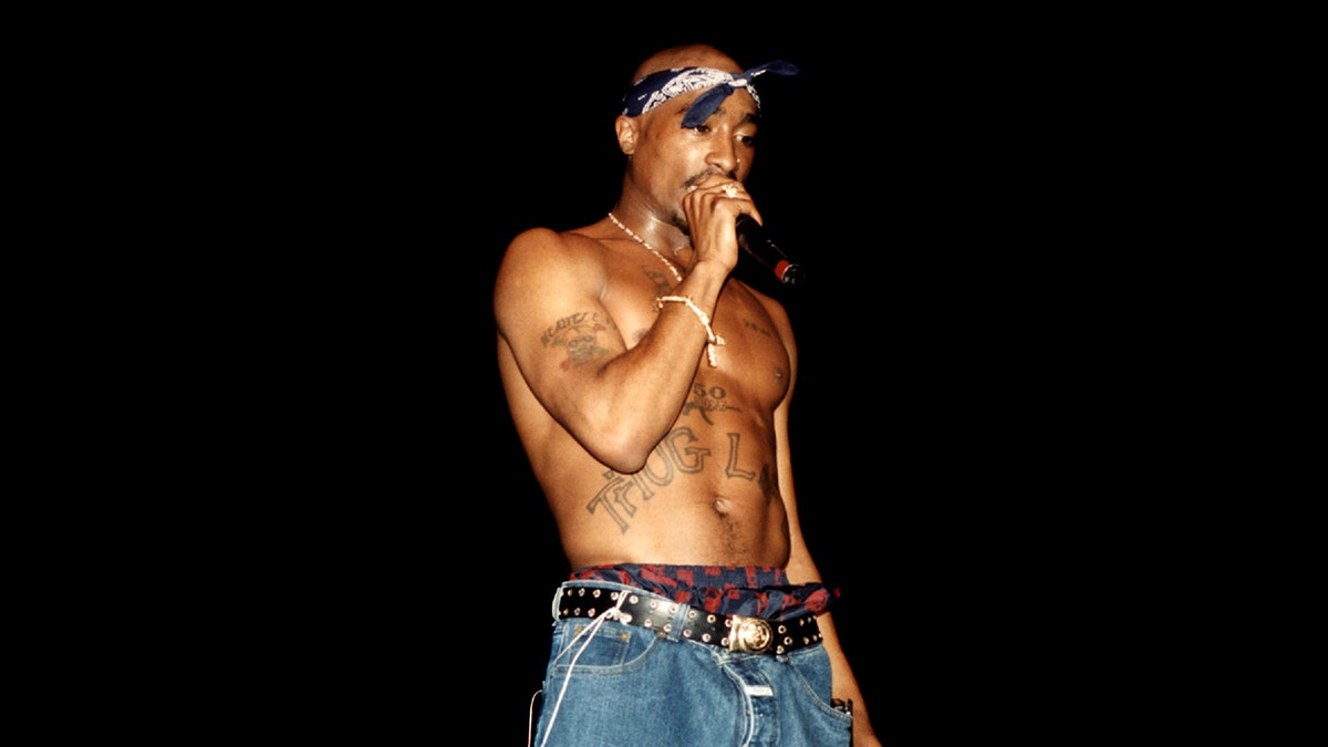 Tupac Shakur raps on stage without a shirt