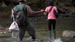 A Haitian migrant man holds a girl's hand as they cross the jungle of the Darien Gap, near Acandi, Choco department, Colombia, heading to Panama, on September 26, 2021, on their way trying to reach the U.S.