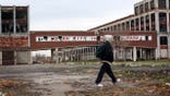 A person walks past the remains of the Packard Motor Car Company, which ceased production in the late 1950s, on Nov. 19, 2008 in Detroit, Michigan.