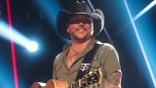Jason Aldean wears black cowboy hat on stage while performing