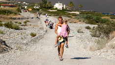 Tourists flee vacation destination 'in just swimsuits' as wildfires rage