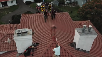 Drone video shows officer scaling house to arrest suspected female intruder perched on roof