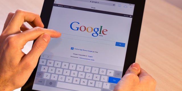 Person holds their iPad with the Google search page on the screen