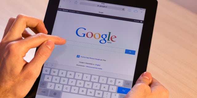 Man holds his iPad with a Google search page on the screen