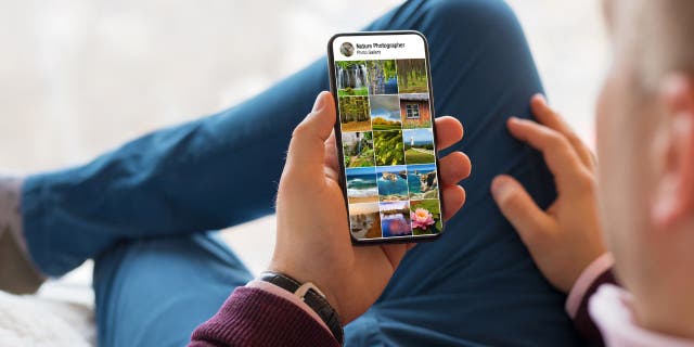 Photo of a man holding up his phone, looking at his photos.