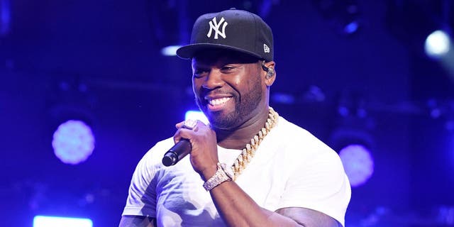50 Cent wearing Yankees cap, holding microphone