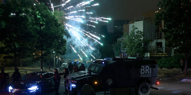 Während der Unruhen in Frankreich explodieren Feuerwerkskörper am Himmel über gepanzerten Fahrzeugen