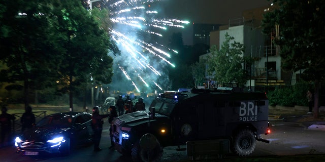 Fireworks explode in the sky above armored vehicles amid France riots