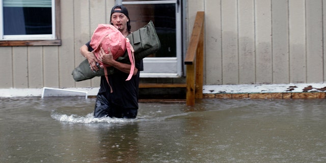 A man carries belongings through floodwaters