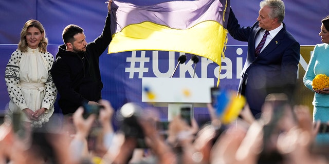 Selenskyj hält eine ukrainische Flagge