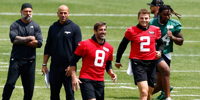 Aaron Rodgers and Zach Wilson warm up before a training session