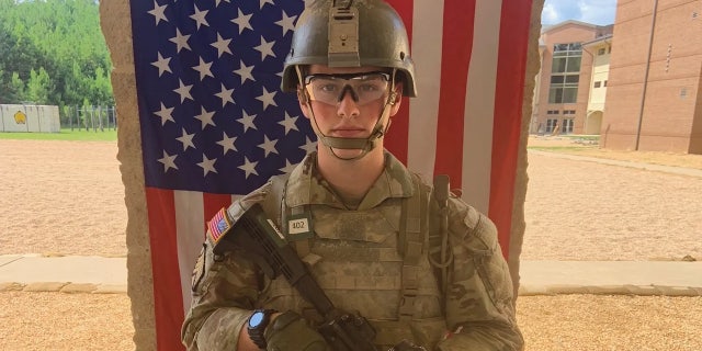 Jacob Aitchison stands in front of an American flag.