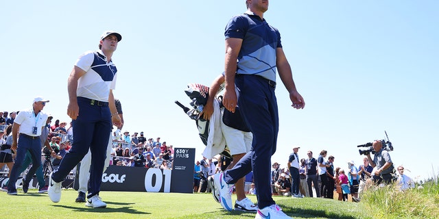 Brooks Koepka and Matt Wolff walk off the first tee