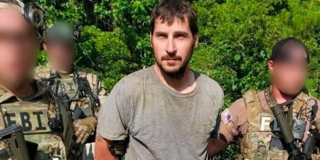 Michael Burham in dirty clothes led out of the woods by FBI