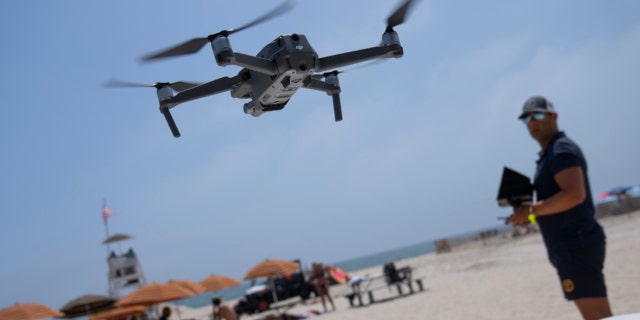 A lifeguard operates a drone