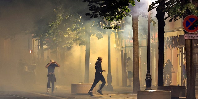 Protestors running away from smoke.