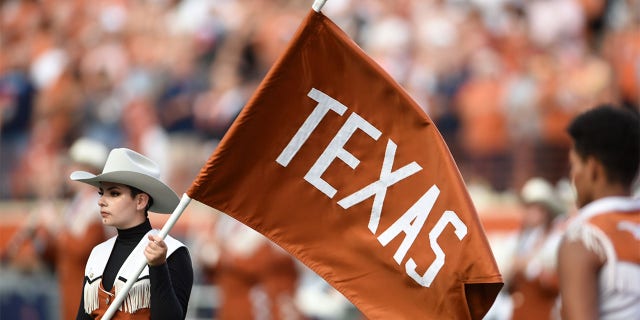 A Texas band member carries the Longhorns flag