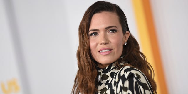 Mandy Moore in a patterned outfit looks to her left on the carpet 
