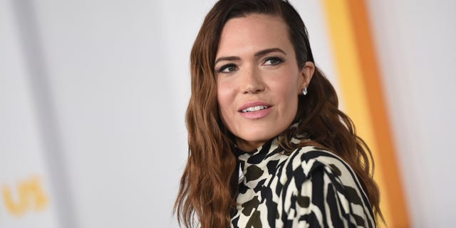 Mandy Moore in a patterned outfit looks to her left on the carpet