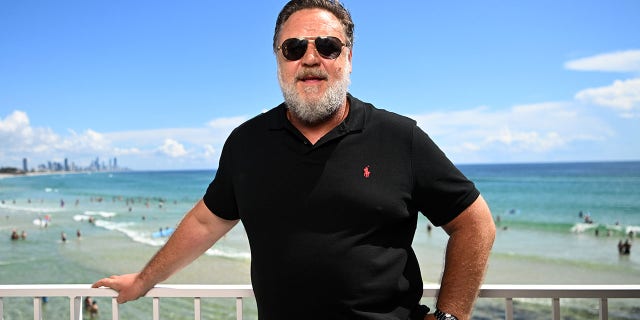 Russell Crowe poses for a photo in front of a beach