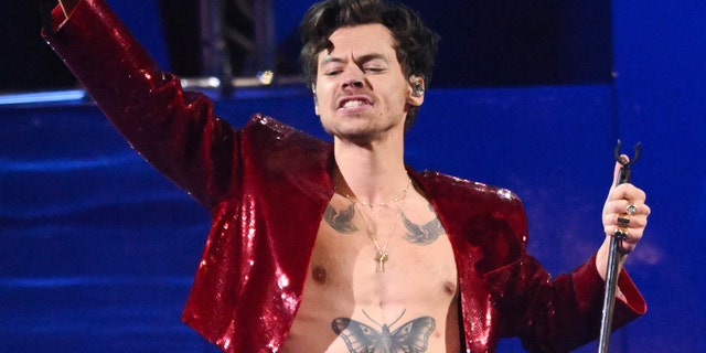 Harry Styles closes his eyes passionately on stage while performing at The BRIT Awards in a sequined jacket and no shirt
