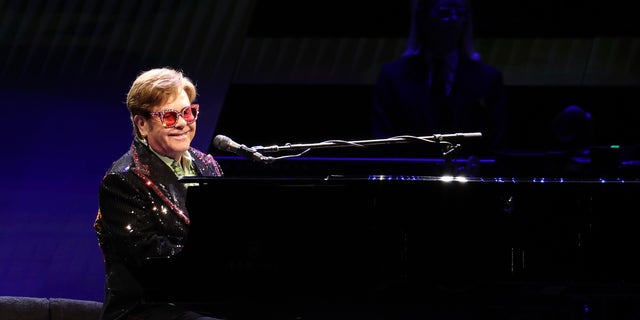 Elton John plays at a piano