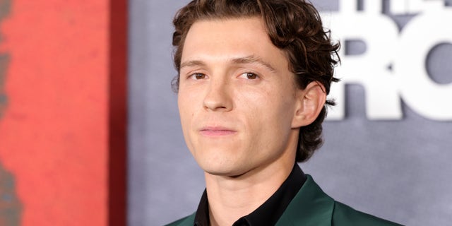 Tom Holland looking serious in a green suit