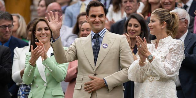 Roger Federer waves his hand as he is the recipient of applause at Wimbledon next to wife Mirka and Kate Middeton