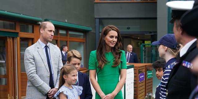 Prince William, Princess Charlotte, Prince George, and Kate Middleton talking with tennis officials