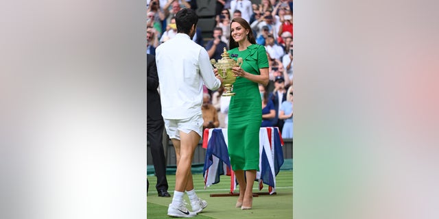 Kate Middleton wearing a green dress presents the Wimbledon trophy to Carlos Alcaraz Garfia