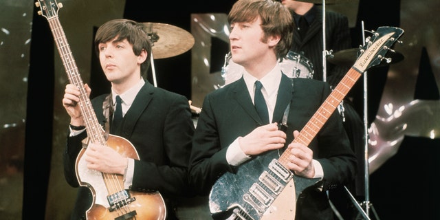 Paul McCartney and John Lennon hold their guitars on The Ed Sullivan Show