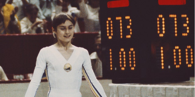 nadia standing by scoreboard reading 1.00