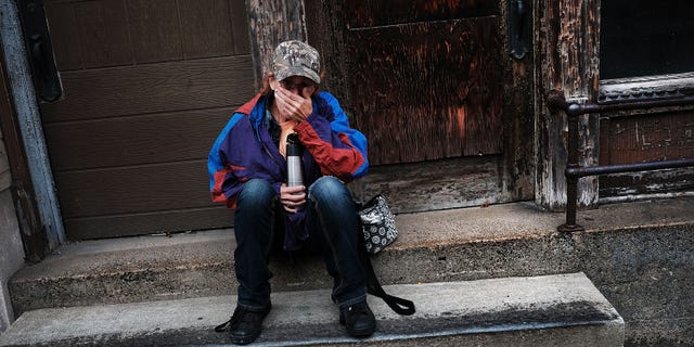 Dora Reynolds, who is unemployed in this picture, sits along a road downtown on Oct. 24, 2016 in East Liverpool, Ohio.