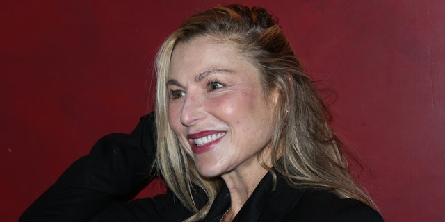 Tatum O'Neal wearing a black suit and smiling.