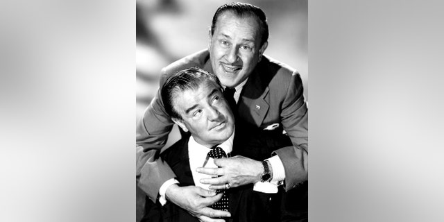 Bud Abbott in a suit embracing Lou Costello who is also in a suit and looking above at Lou Costello