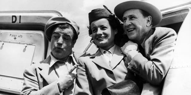 Lou Costello pointing at a servicewoman with Bud Abbott leaning in and smiling