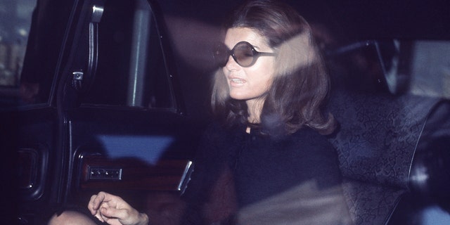 Jackie Kennedy wearing black sitting in the back of a car