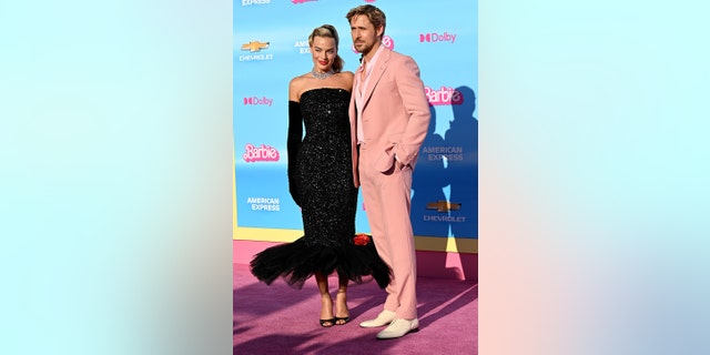 Margot Robbie wearing a vintage black Barbie dress posing next to Ryan Gosling in a pink suit