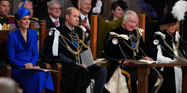 Kate Middleton in a blue dress sitting next to Prince William, King Charles and Queen Camilla