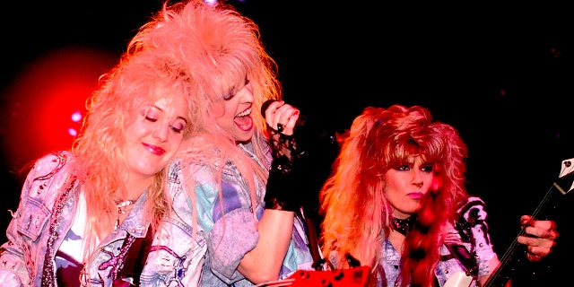 The band Vixen performing close to each other on stage wearing denim jackets