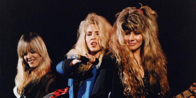 The band Vixen huddled together and performing in 1991
