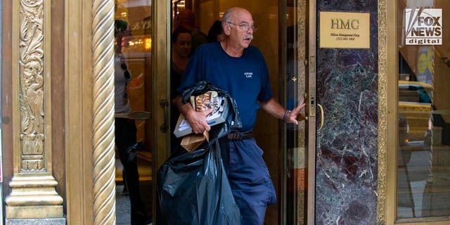 A Suffolk County Crime Lab detective carries items out of 385 Fifth Avenue