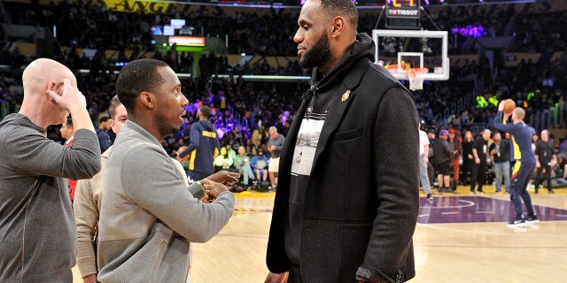 Rich Paul and LeBron James talk during a game