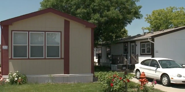 A brown trailer with white car in driveway