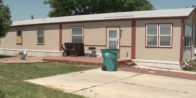 Beige trailer with a bedroom window boarded up.