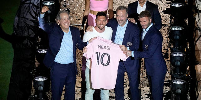 Lionel Messi sostiene la camiseta rosa