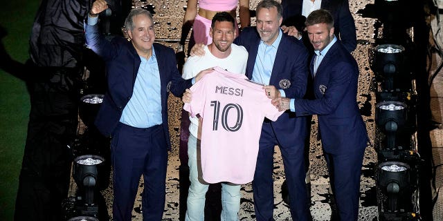 Lionel Messi holds the pink shirt