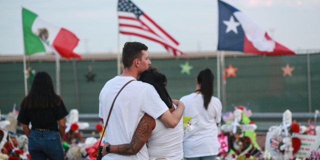 People gather at a makeshift memorial outside the El Paso, Texas, Walmart